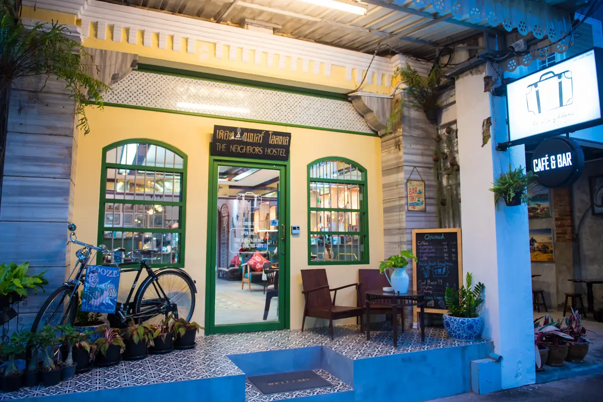 Pale yellow shopfront with green arched windows, a bicycle and tiled steps.