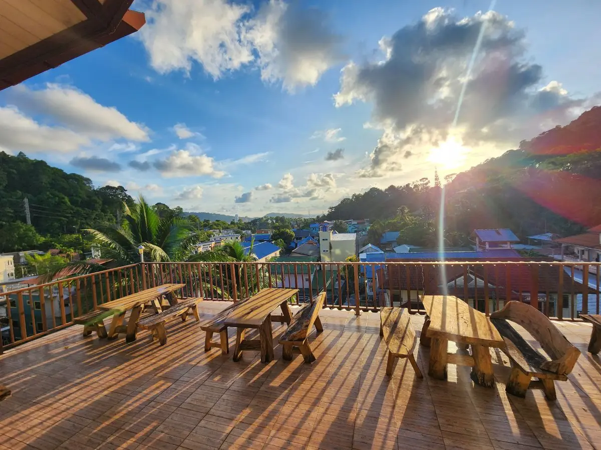 Wooden terrace with picnic benches and a view over a bay at sunset.