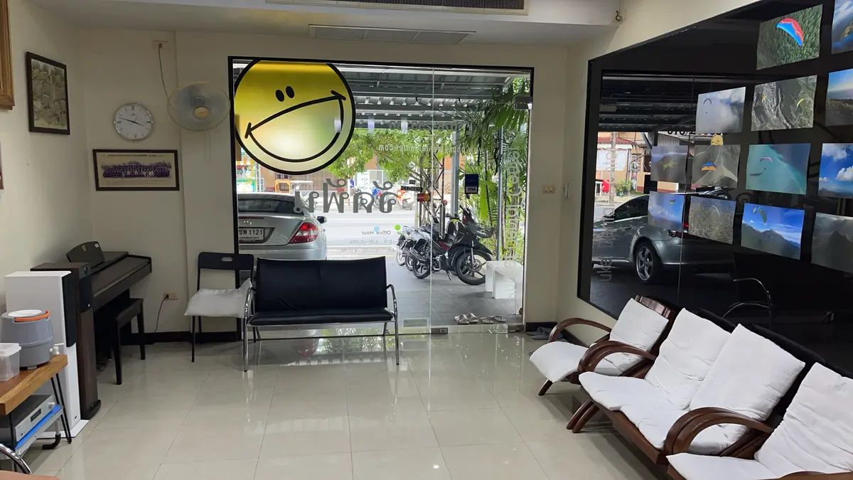 Empty waiting area with a black bench, wooden chairs and a glass door onto the street.