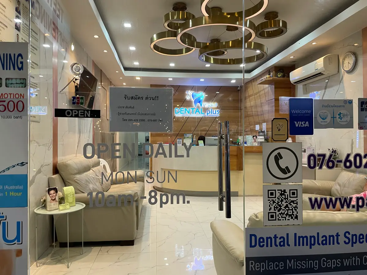 Clinic waiting area with a beige sofa, a gold ring ceiling light and signs on the glass door.