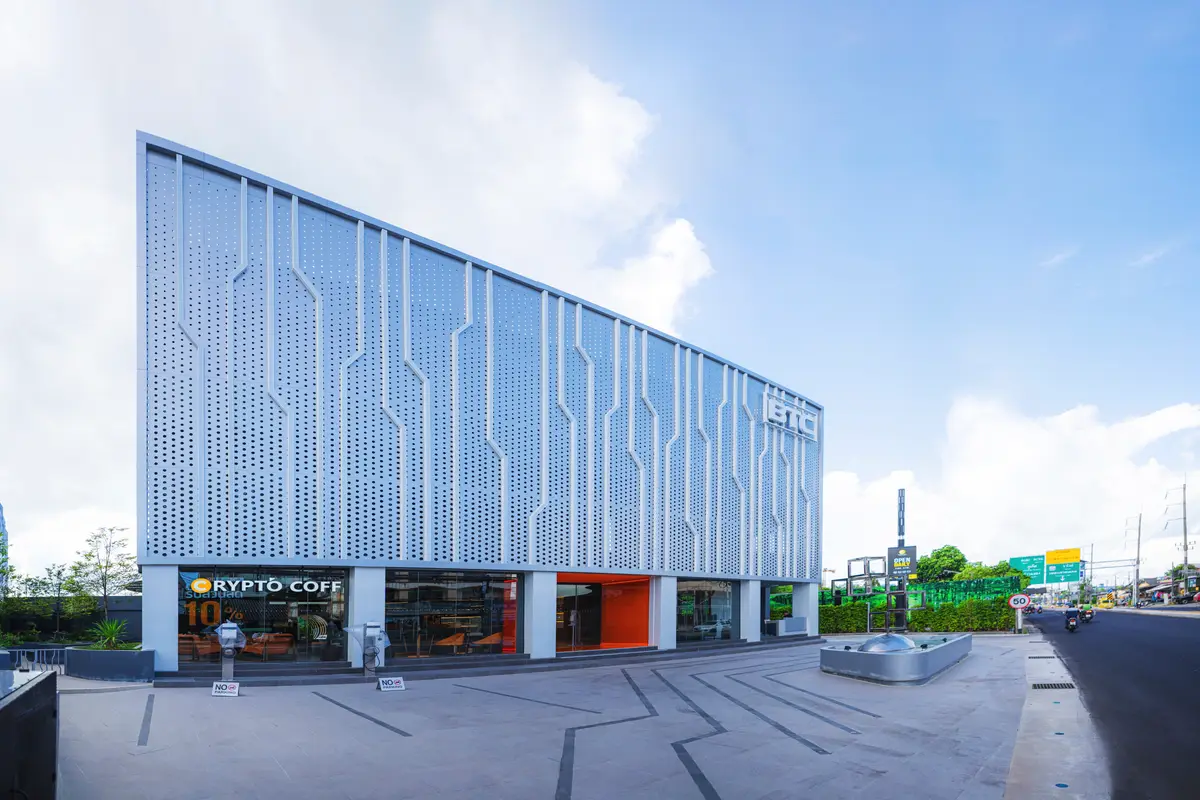 Modern white building with a patterned facade seen from the road.