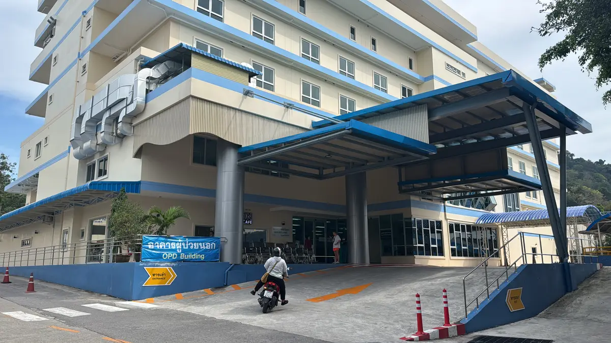 Blue and white hospital building with a covered entrance driveway and an outpatient sign at street level.