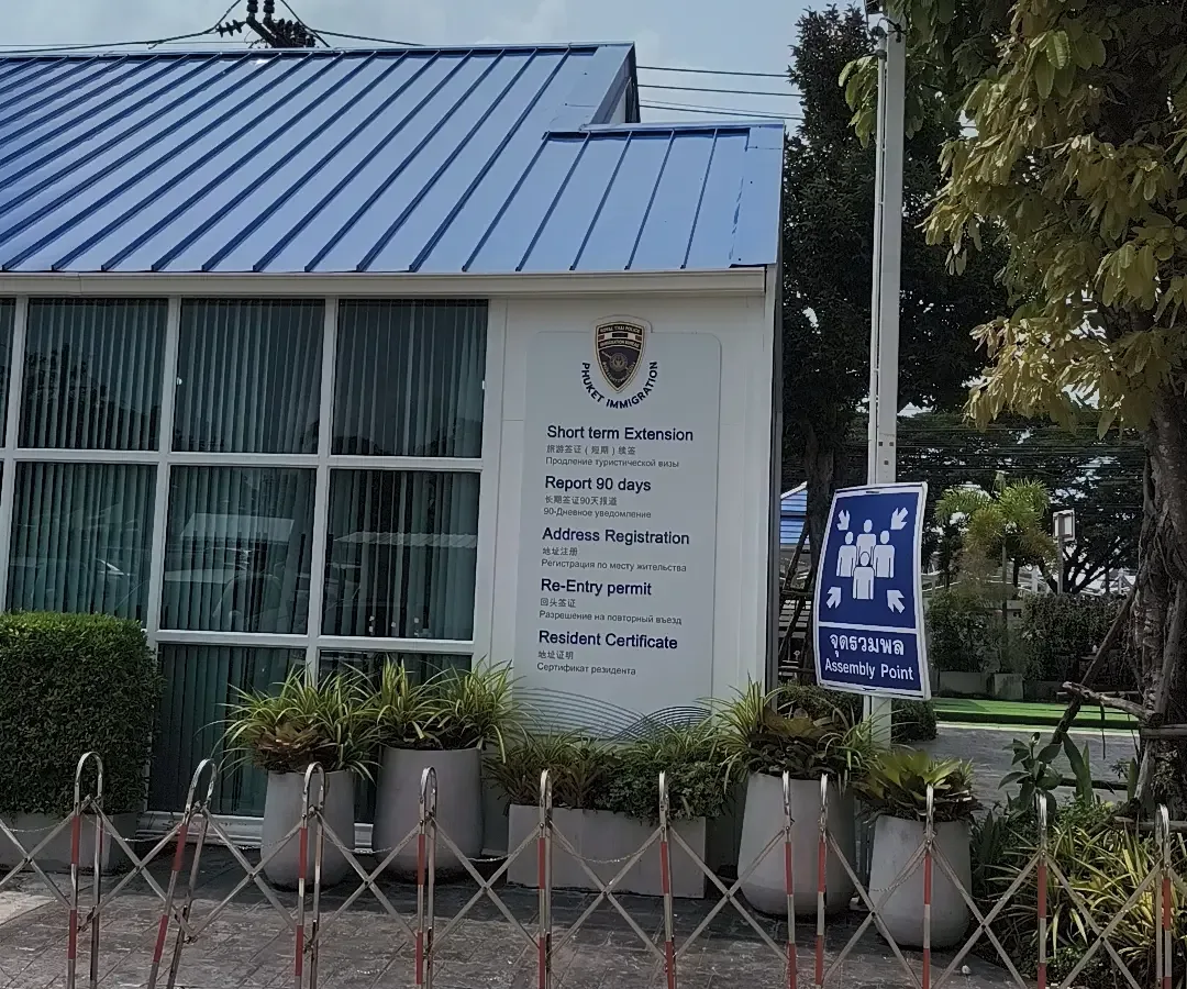 Blue-roofed office building with a service board beside the entrance listing extension, address registration, re-entry permit and resident certificate services.