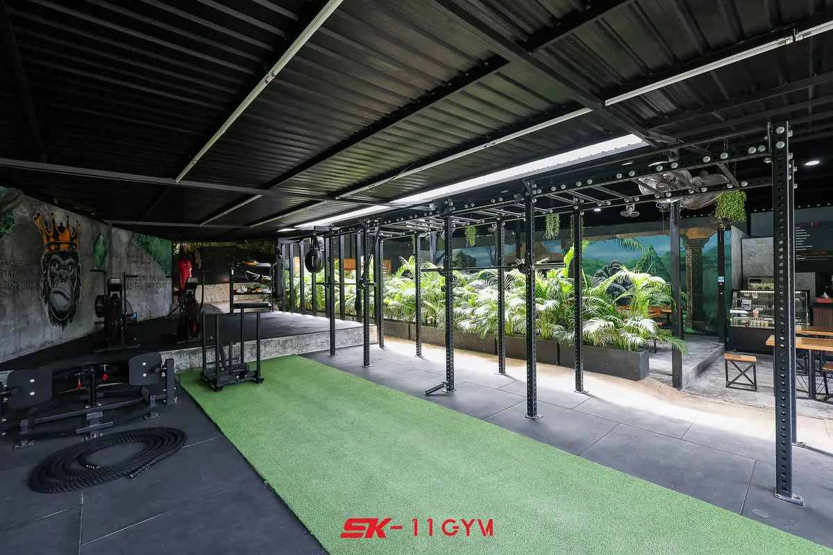 Outdoor training area with green turf and steel racks under a roof.