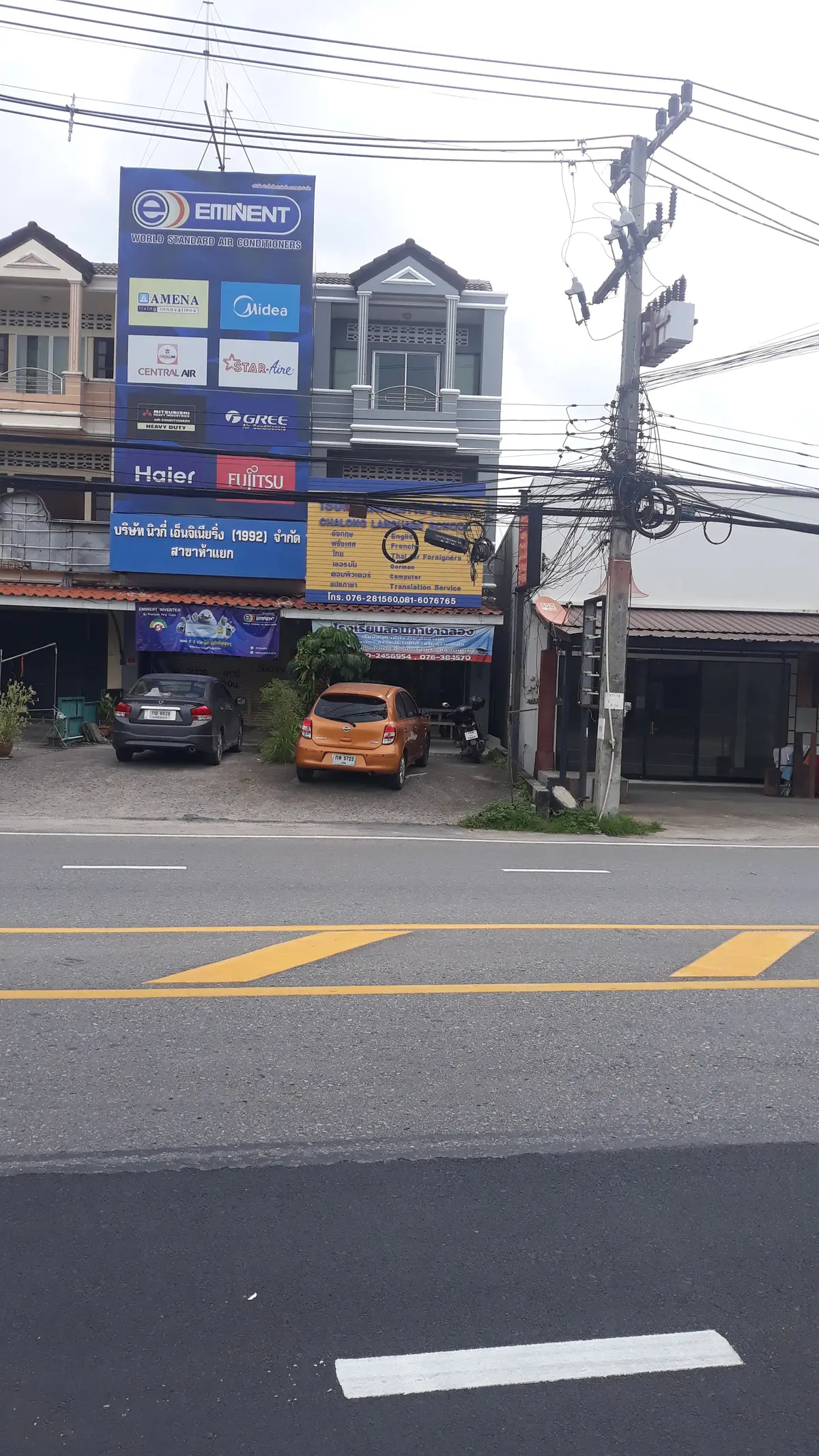 Street frontage of a shophouse with blue signboards above a small car park.