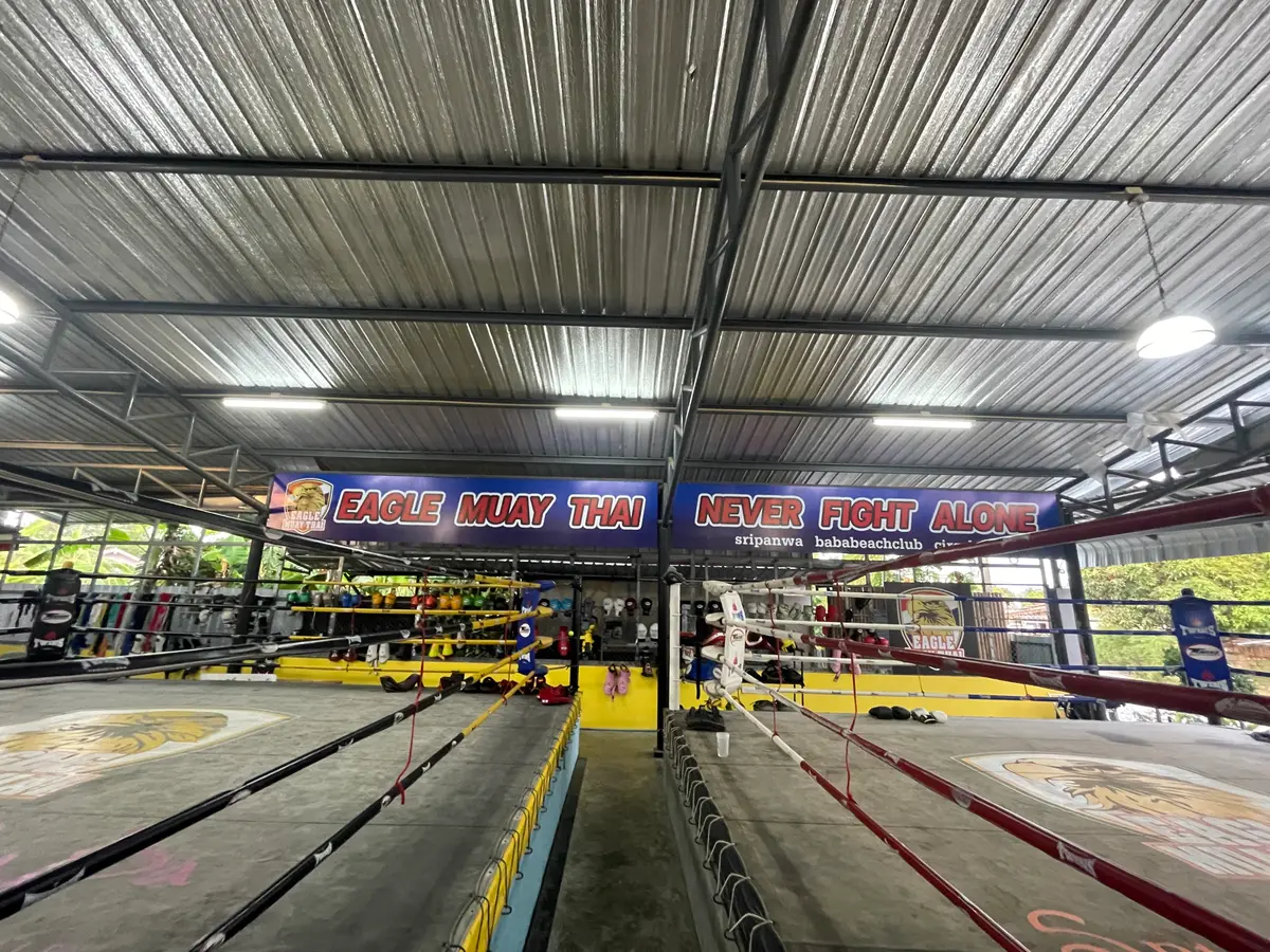 Two boxing rings under a metal roof with a banner above them.