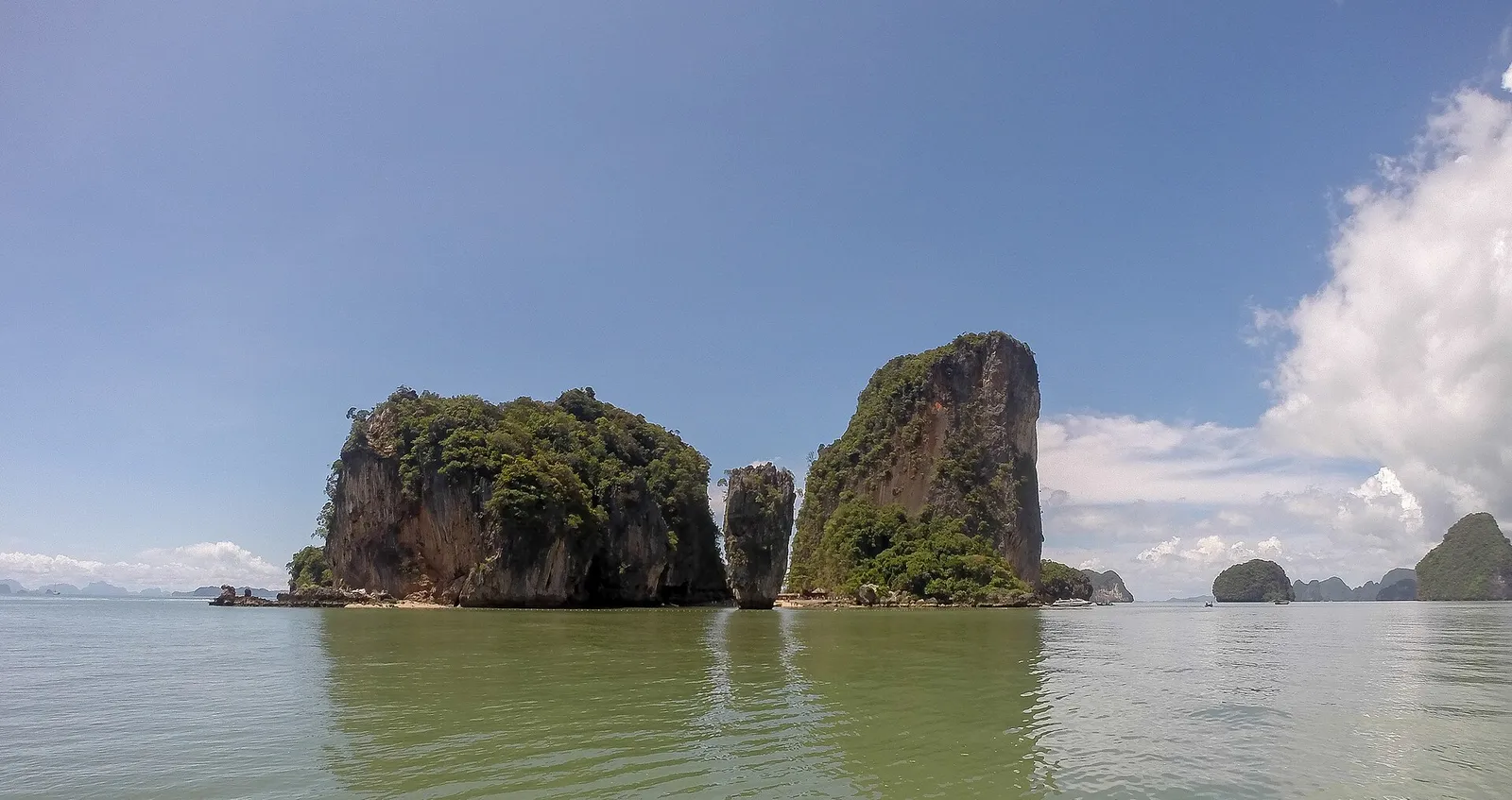 Two rocky limestone outcrops covered in green scrub rising from calm water at Khao Phing Kan.