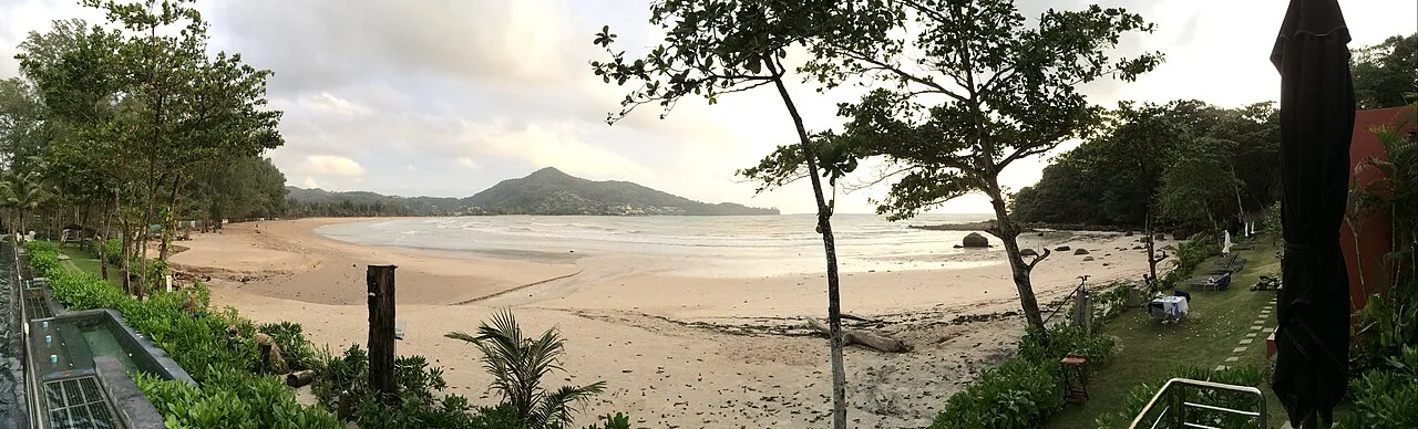 Wide empty sand at low tide with a hill on the far side of the bay at Kamala.