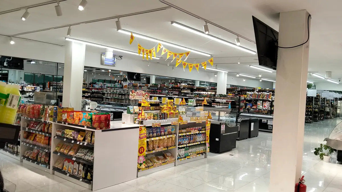 Bright supermarket interior with a checkout counter and stocked aisles behind it.