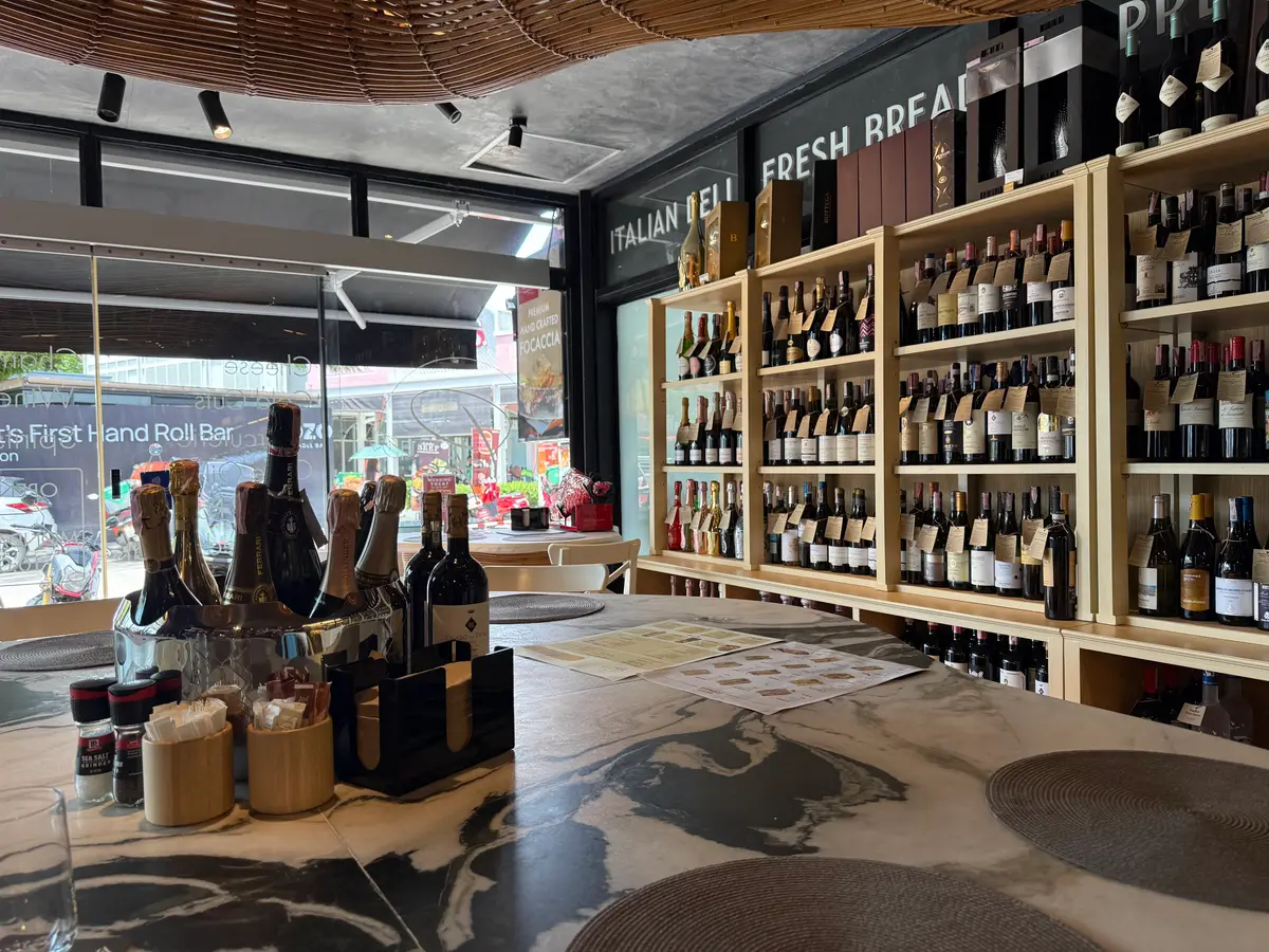 Wooden wall shelves full of wine bottles beside a marble table.