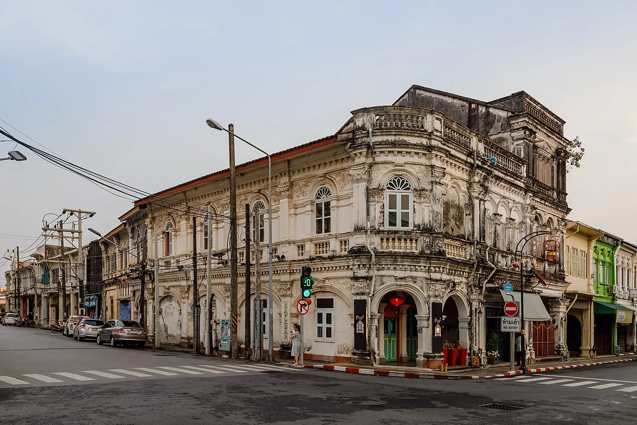 Two-storey Sino-Portuguese shophouse on a street corner in Phuket Old Town, with arched ground-floor openings and carved upper windows.