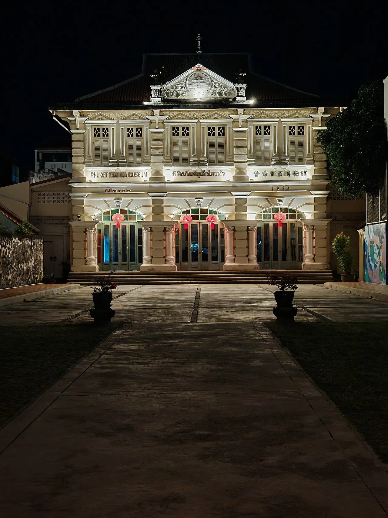 The Thai Hua Museum front lit up after dark, with lanterns under the arched windows.