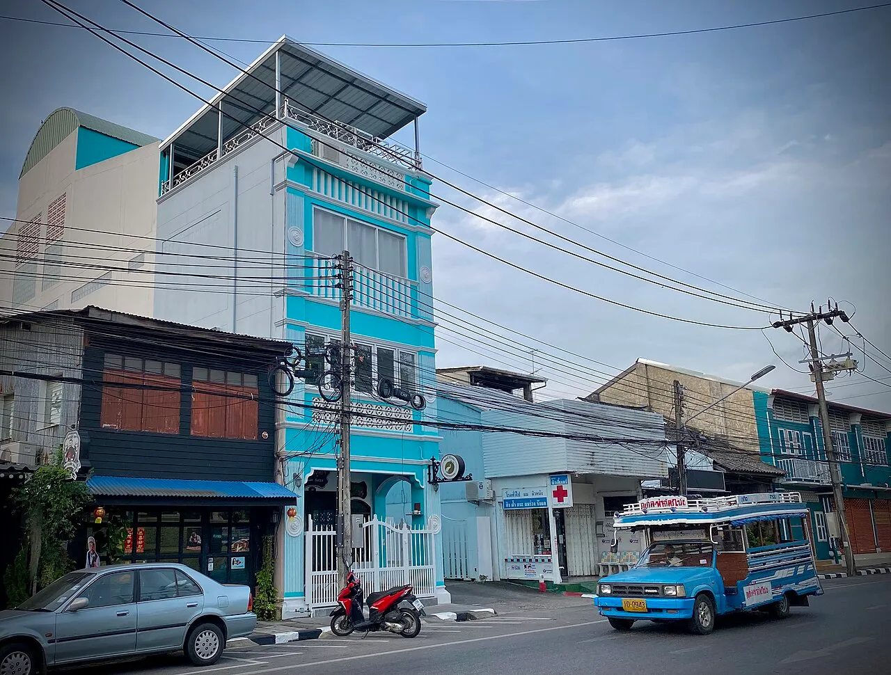 Blue songthaew truck passing colourful shophouses on a Phuket street
