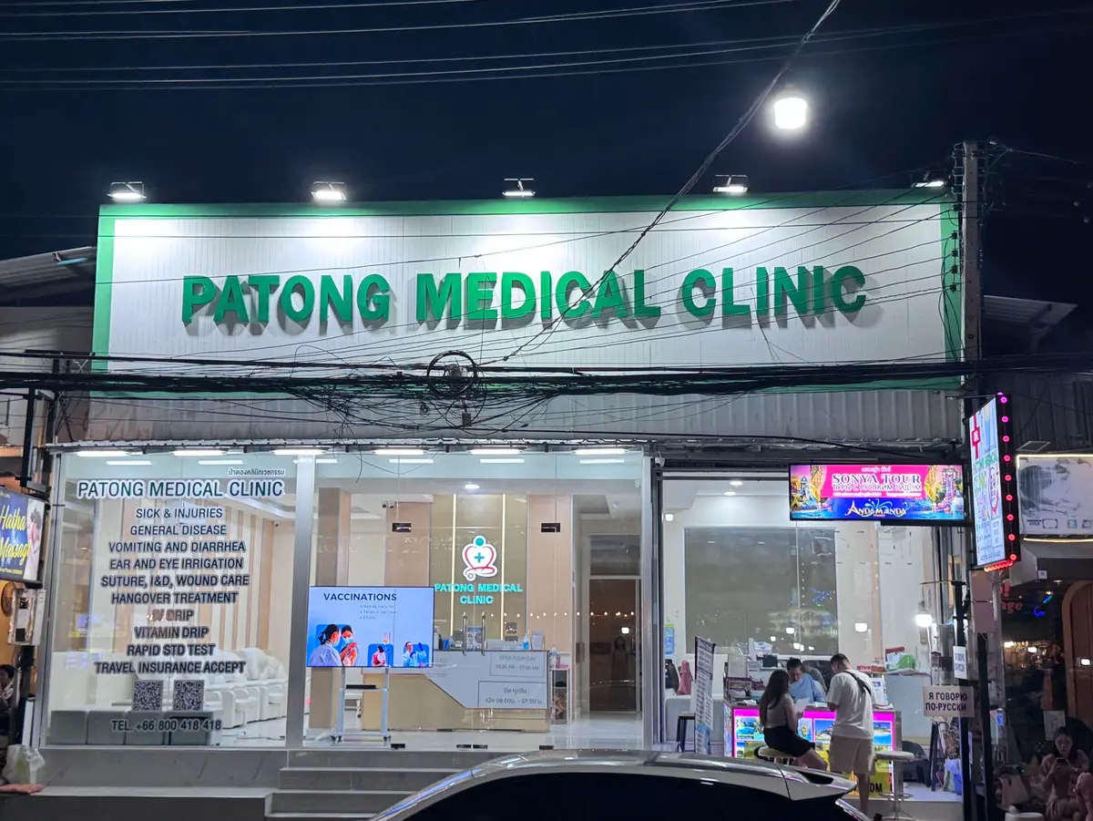 Night view of a glass-fronted clinic with a green sign reading Patong Medical Clinic above the entrance.