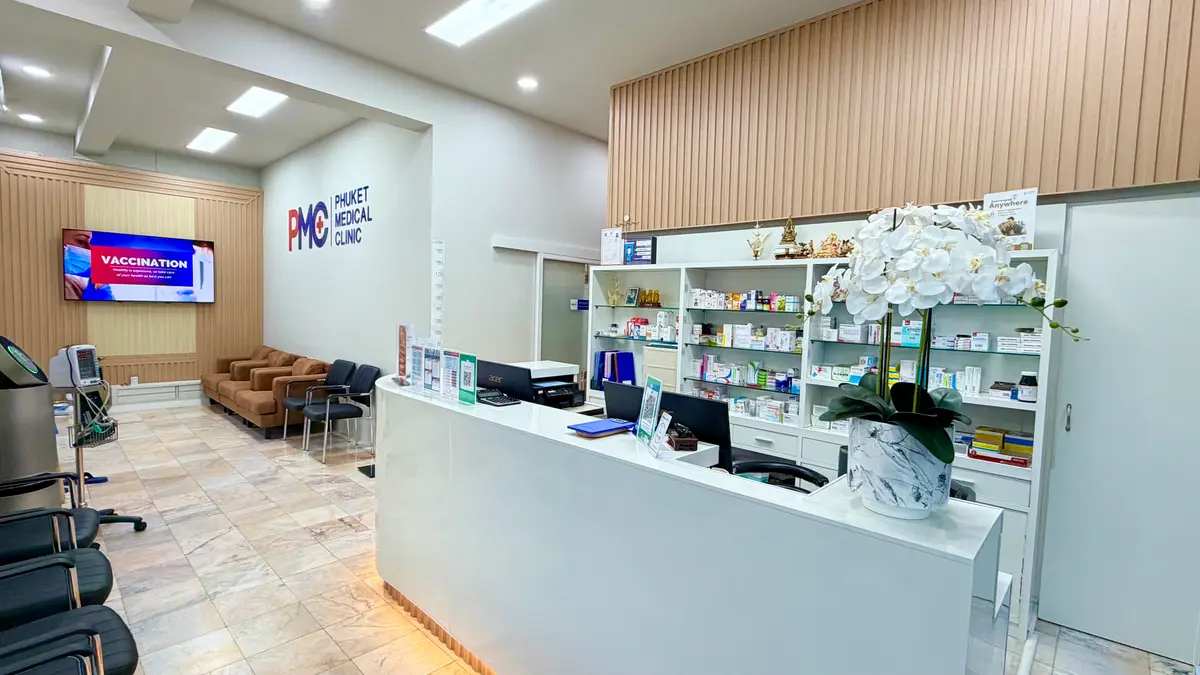 White reception counter with shelves of medicine boxes and a brown sofa behind it.