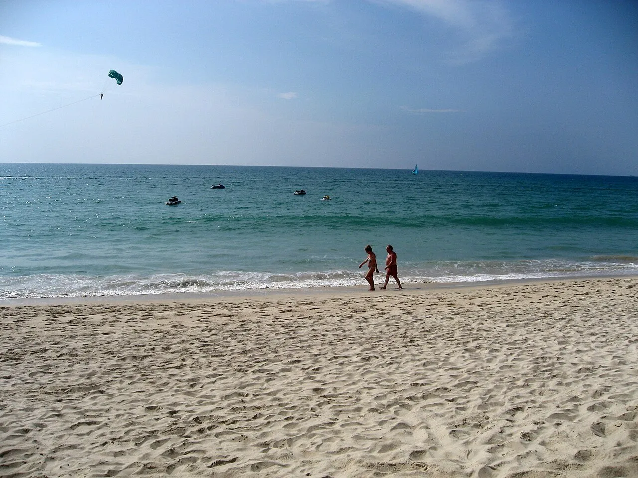 Long flat sandy beach under a clear sky with calm blue-green sea at Bang Tao.