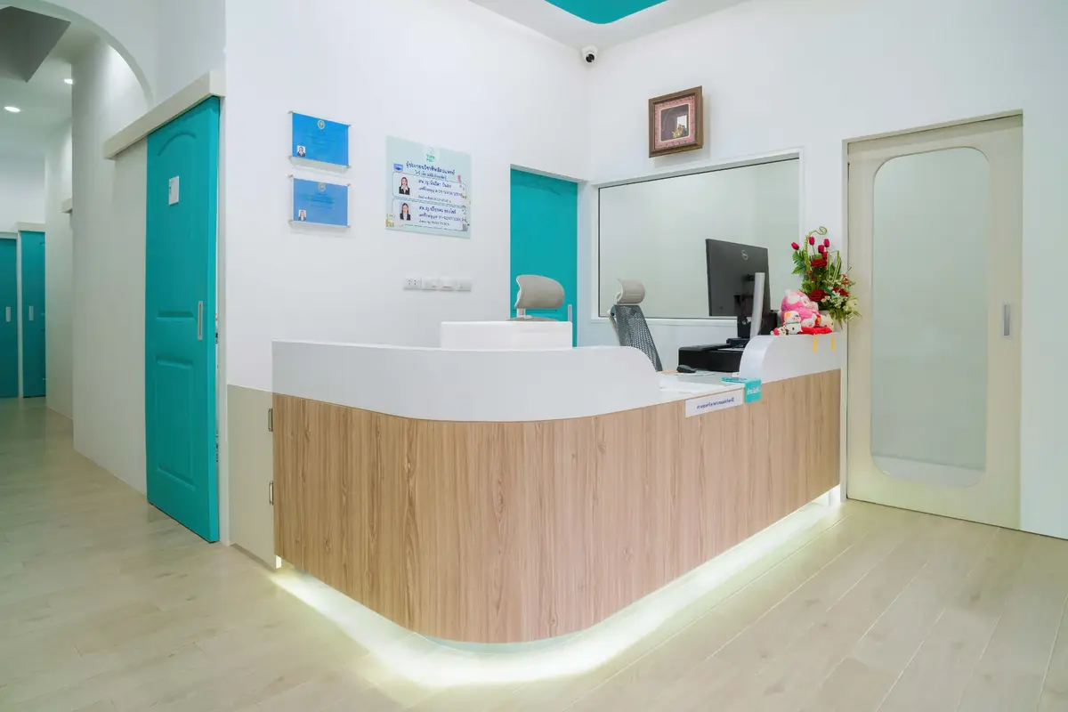 Clinic reception with a wood-fronted counter and teal doors.